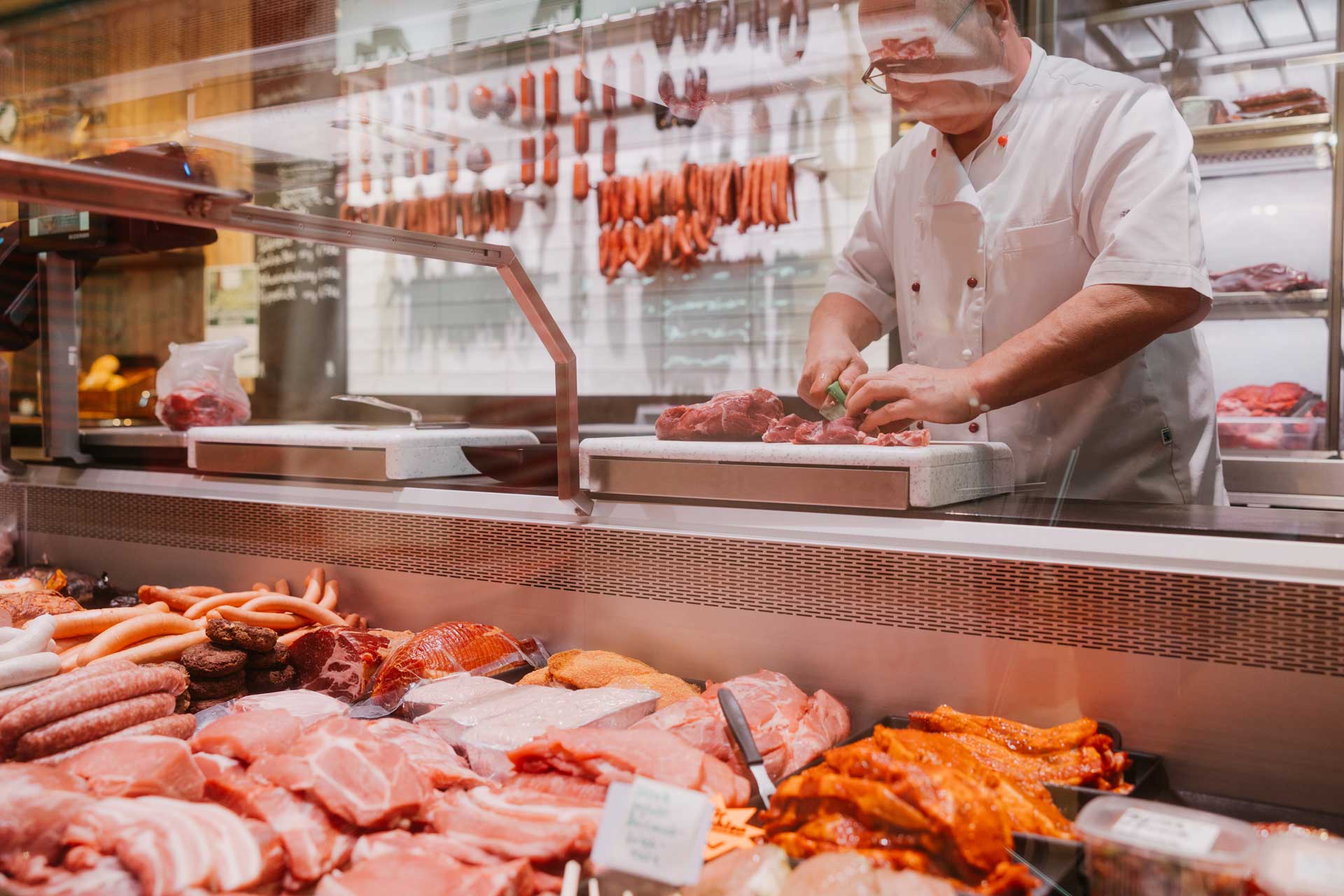 Metzger an der Frischetheke mit Wurst und Fleisch
